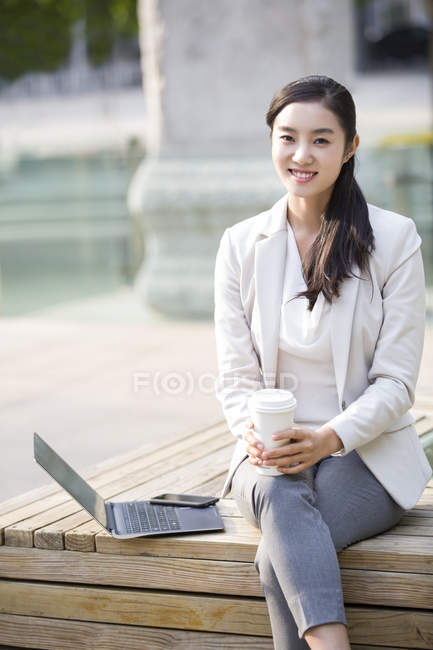 Femme d'affaires chinoise assis avec ordinateur portable et café — Photo de stock