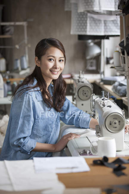 Créateur de mode chinois travaillant avec une machine à coudre en studio — Photo de stock