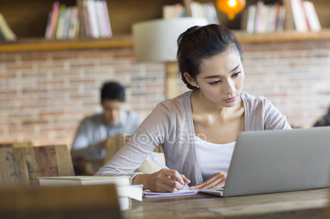 Chinese female student studying with laptop in cafe — Stock Photo