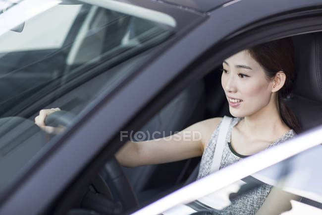 Chinesin sitzt im Auto und hält Lenkrad — Stockfoto