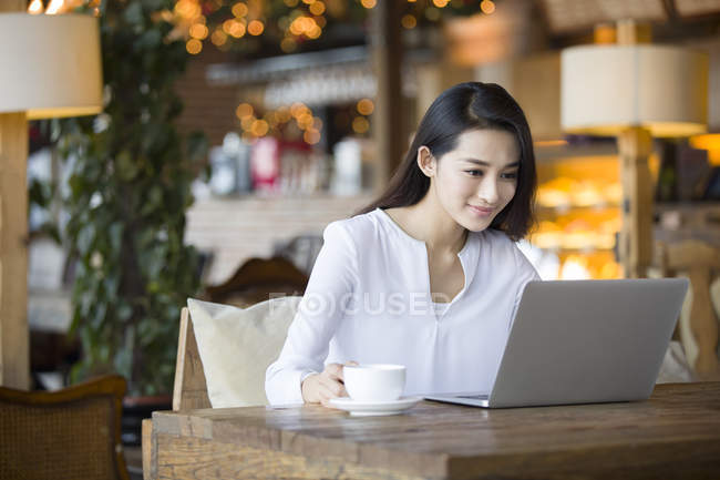 Китаянка использует ноутбук в кафе — стоковое фото