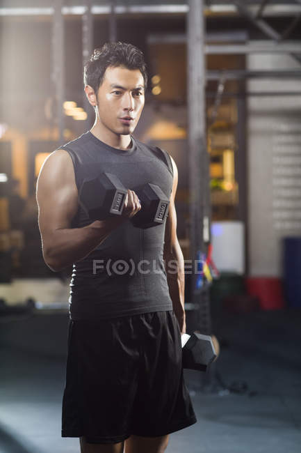 Chinois homme levant haltères à la salle de gym — Photo de stock
