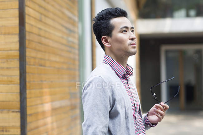 Китайський чоловік тримає окуляри на вулиці — стокове фото