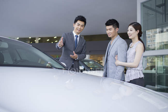 Couple chinois choisir une voiture avec concessionnaire dans le showroom — Photo de stock