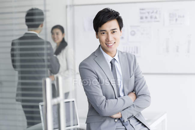 Hombre de negocios chino sentado con los brazos cruzados - foto de stock