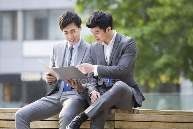 Chinese businessmen working with documents on street — Stock Photo