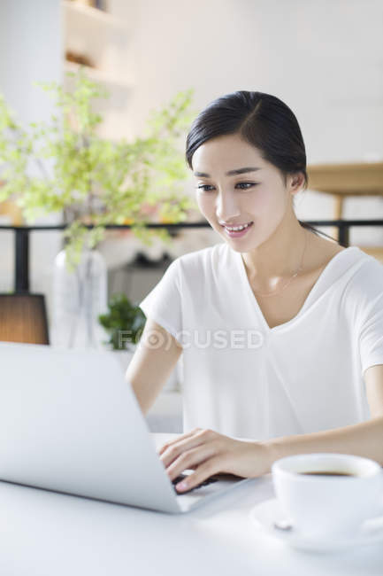 Mujer china usando el ordenador portátil en la cafetería - foto de stock