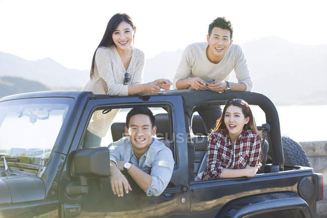 Chinese friends sitting in car and looking in camera — Stock Photo