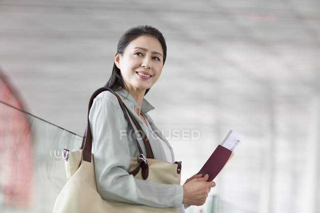 Зрелая китаянка ждет в аэропорту с билетом — стоковое фото