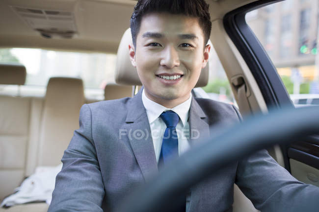 Chinese chauffeur sitting in car and smiling — Stock Photo