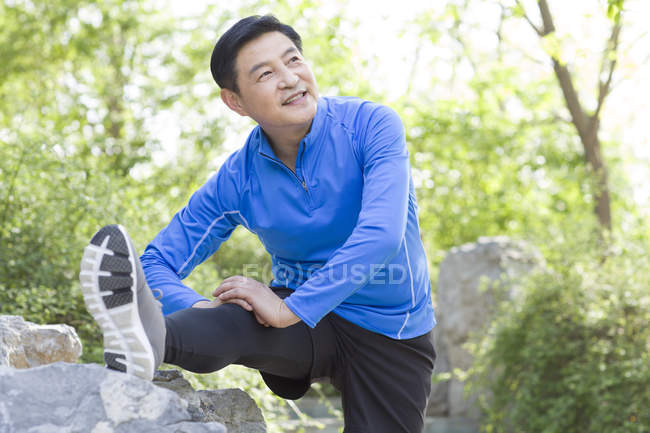 Maturo cinese uomo stretching in parco — Foto stock