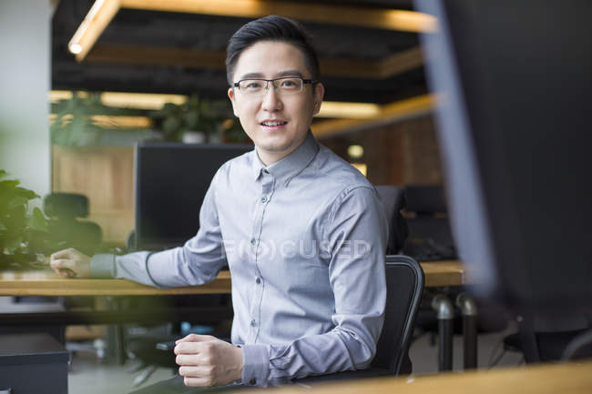 Trabalhador chinês de TI sentado no local de trabalho — Fotografia de Stock