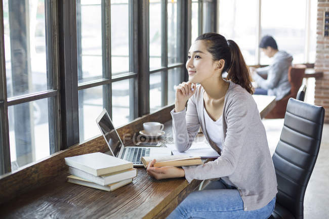 Chinese female student studying with books in cafe — Stock Photo