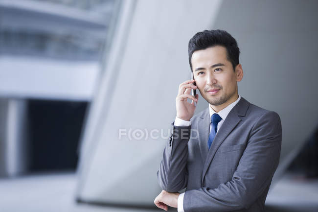 Homem de negócios chinês falando ao telefone e olhando para a vista — Fotografia de Stock