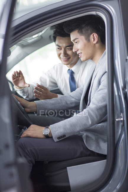 Negociante de carro ajudando o homem com test drive — Fotografia de Stock