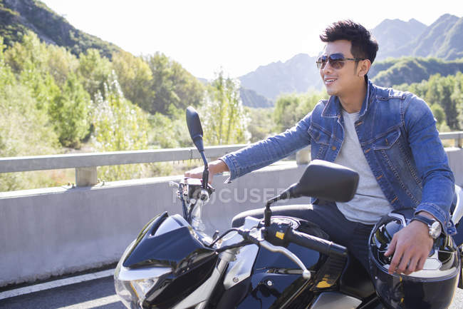 Chinese man sitting on motorcycle on highway — Stock Photo