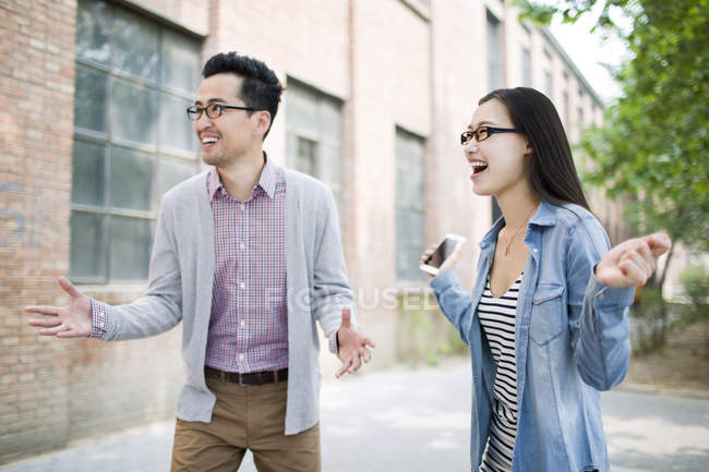 Китайские коллеги смотрят в сторону и смеются на улице — стоковое фото