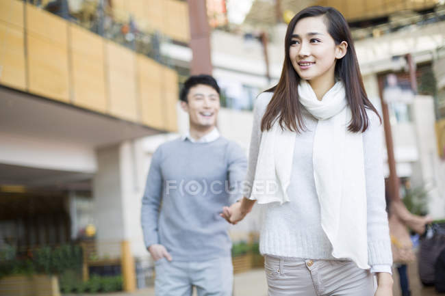 Mujer china y hombre tomados de la mano mientras compran en el centro comercial - foto de stock