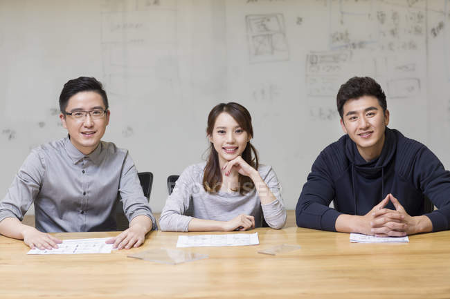 Chinese IT workers sitting in board room and looking in camera — Stock Photo