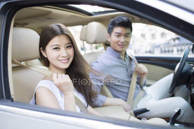 Pareja china sentada en coche - foto de stock