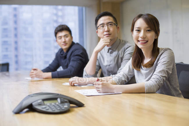 Mulher chinesa sorrindo na reunião com colegas na sala de bordo — Fotografia de Stock