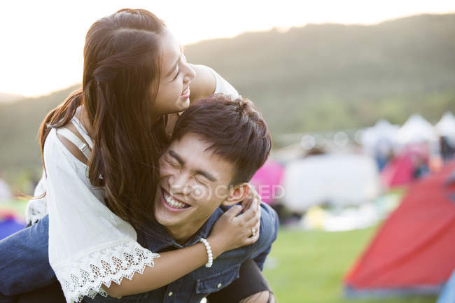 Chinese couple riding piggyback at festival camping — Stock Photo