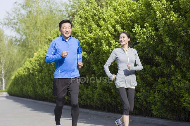 China pareja madura corriendo en parque - foto de stock