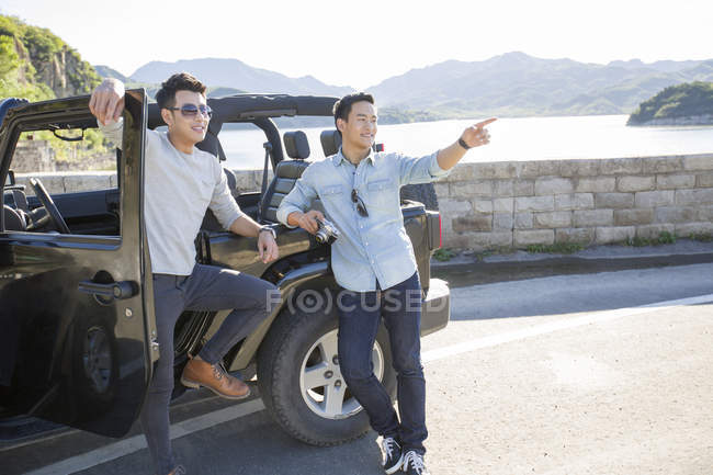 Chineses homens apoiados no carro em subúrbios e apontando — Fotografia de Stock