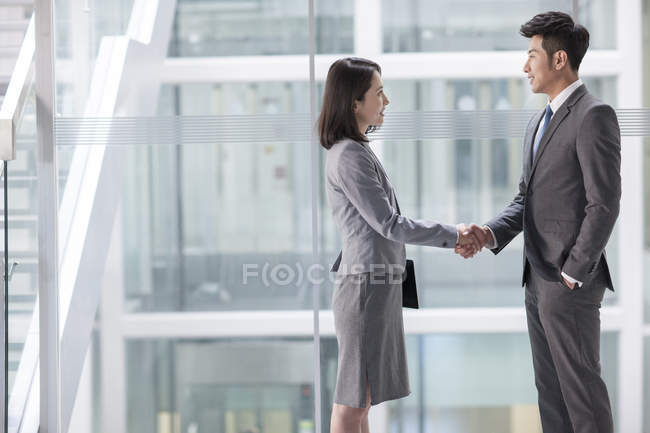 Chinese business people shaking hands in office building — Stock Photo