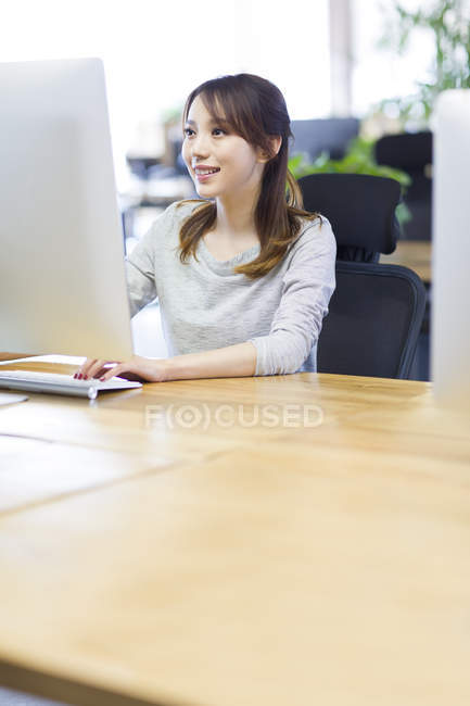 Mulher chinesa trabalhando com computador no escritório — Fotografia de Stock