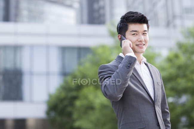 Hombre de negocios chino hablando por teléfono en la calle - foto de stock