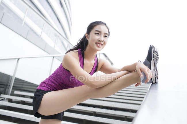 Mujer china estirándose en las escaleras de la calle - foto de stock