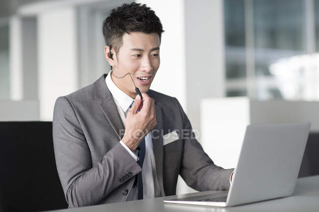 Китайский менеджер по продажам с гарнитурой на ноутбуке — стоковое фото