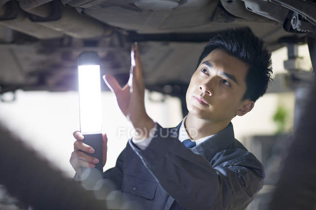 Chinesischer Automechaniker untersucht Auto mit Taschenlampe — Stockfoto