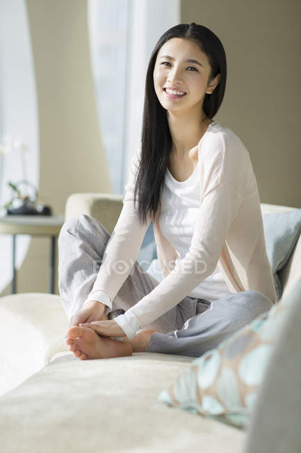 Chinese woman sitting on sofa in home interior — Stock Photo