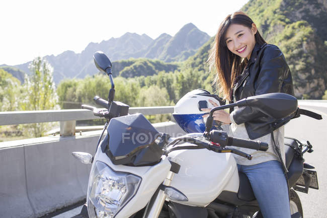 Femme chinoise assise sur une moto avec casque — Photo de stock