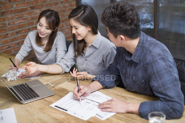 Chinese co-workers sitting at meeting room with laptop — Stock Photo