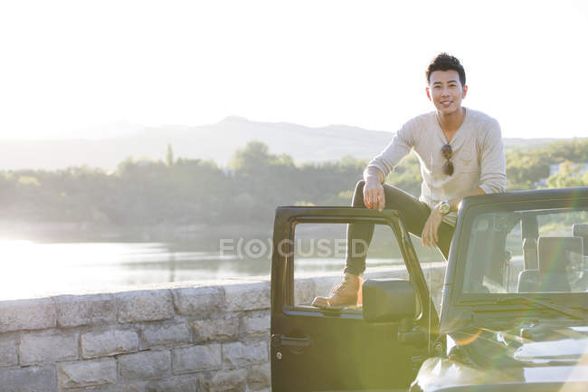 Chinês homem de pé no carro em subúrbios — Fotografia de Stock