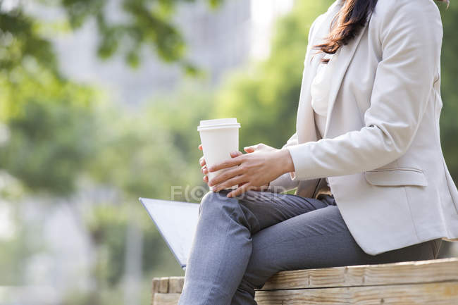 Femme d'affaires assis avec ordinateur portable et café — Photo de stock