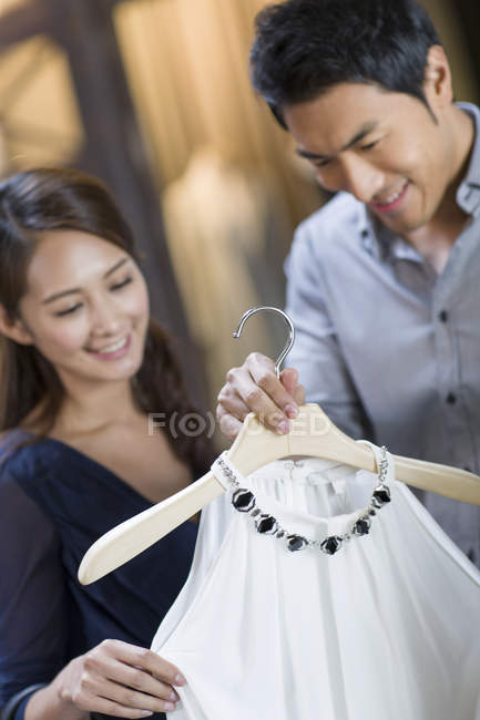 Casal chinês escolhendo vestido na loja de roupas — Fotografia de Stock