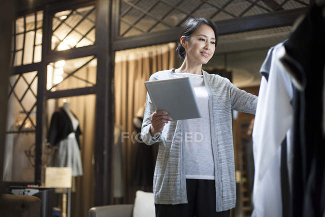 Владелец китайского магазина одежды стоит с цифровым планшетом — стоковое фото