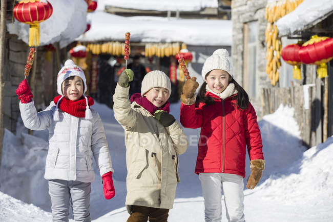 Chinese children holding candied haws and looking in camera — Stock Photo