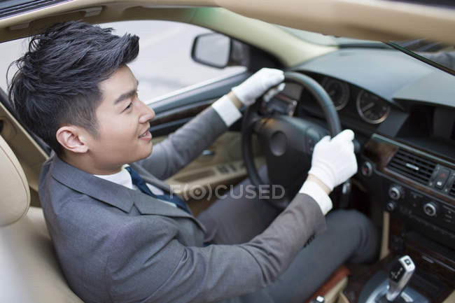 Chófer chino conduciendo coche y mirando hacia otro lado - foto de stock