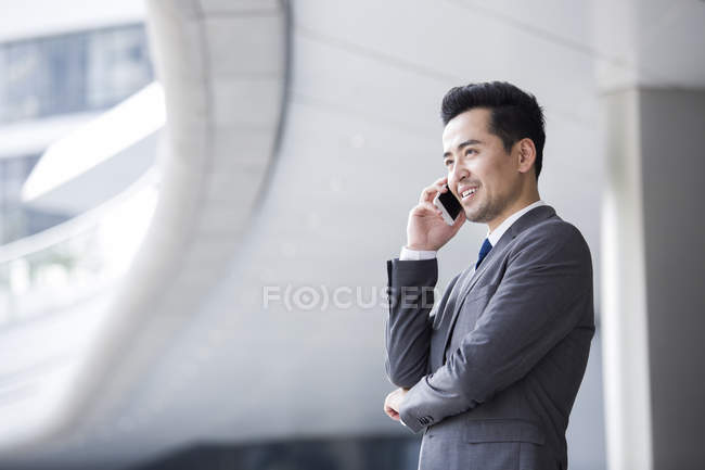 Hombre de negocios chino hablando por teléfono, vista lateral - foto de stock