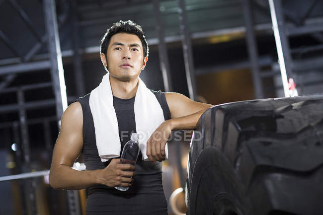 Chinese man resting at gym with water — Stock Photo