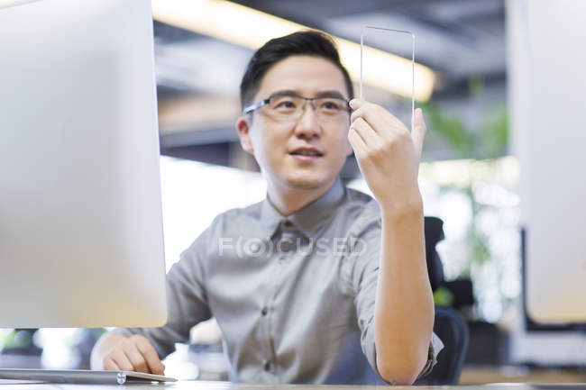 Китайський його працівник розвивається смартфон в офісі — стокове фото