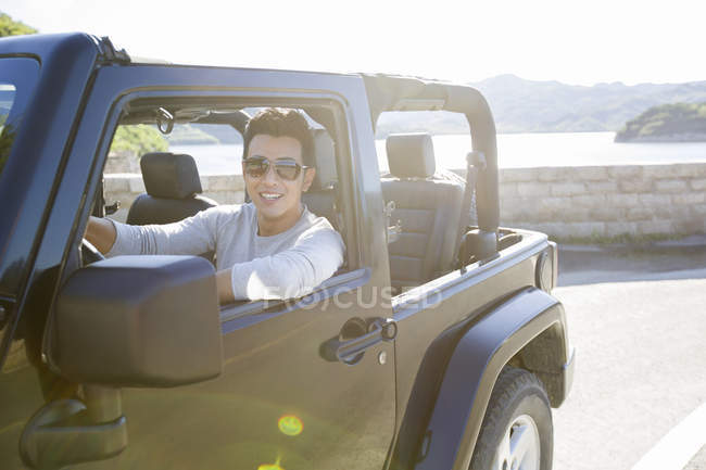 Homem chinês dirigindo carro e olhando na câmera — Fotografia de Stock