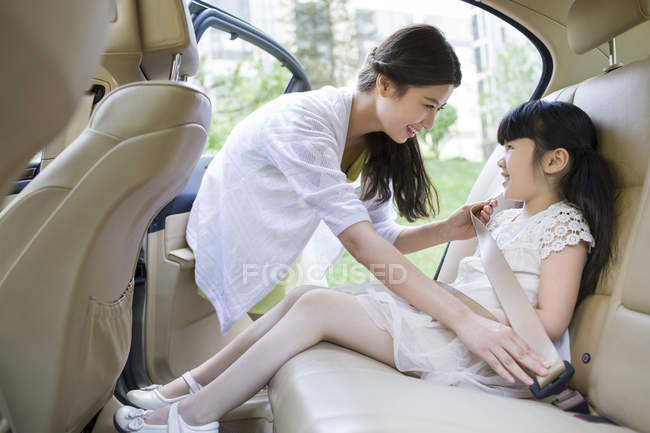 Chinese mother fastening seat belt for daughter — Stock Photo