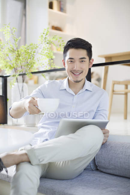 Китаец сидит с цифровым планшетом в кофейне — стоковое фото