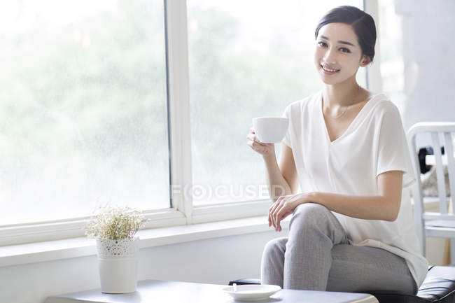 Китаянка держит кофе в кафе — стоковое фото